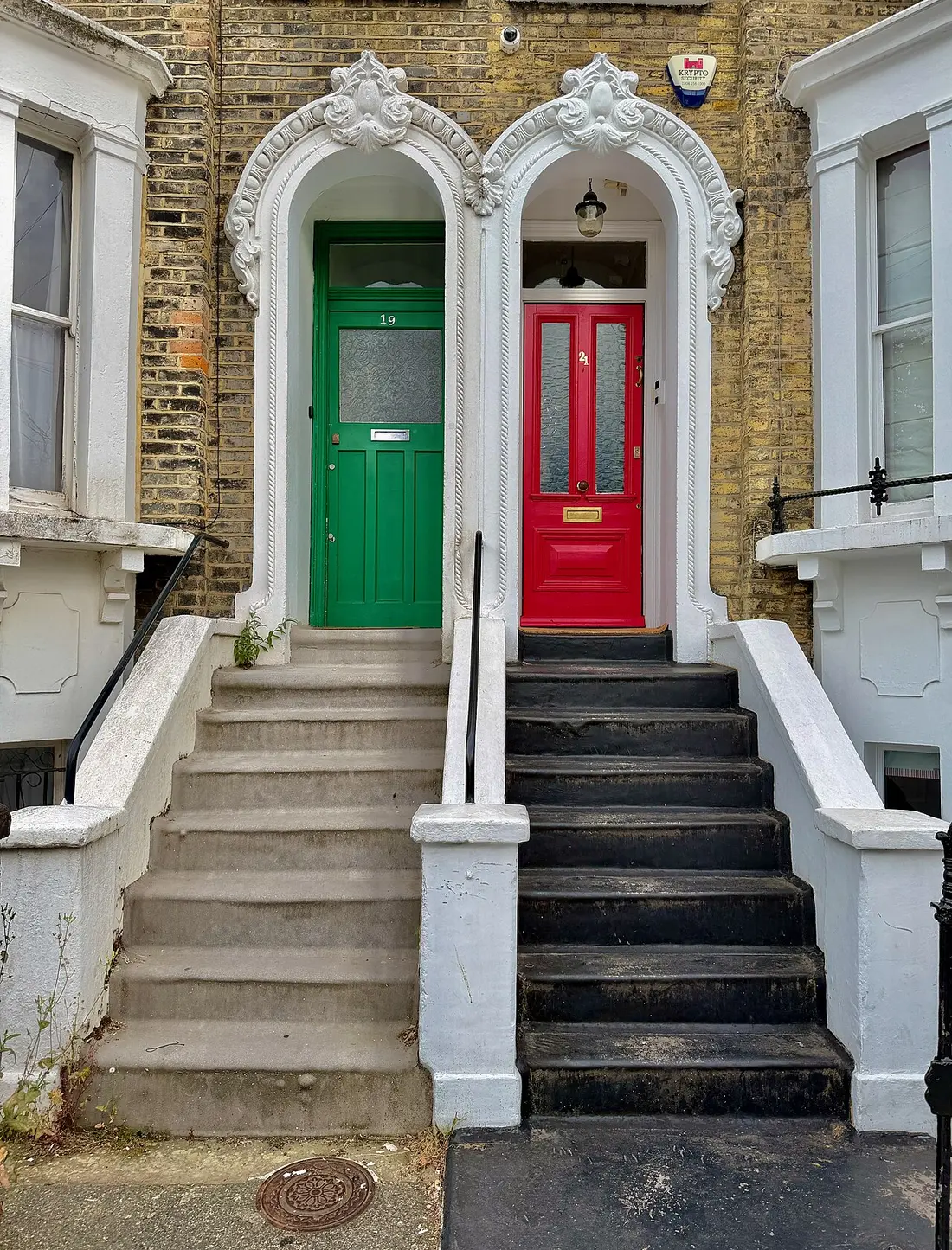 A green and a red front door side by side on Alderney Road, London